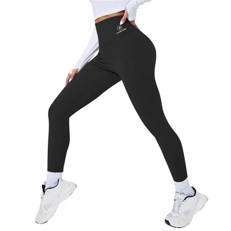Black high-waist workout leggings with white logo, paired with white sneakers and crop top for fitness fashion