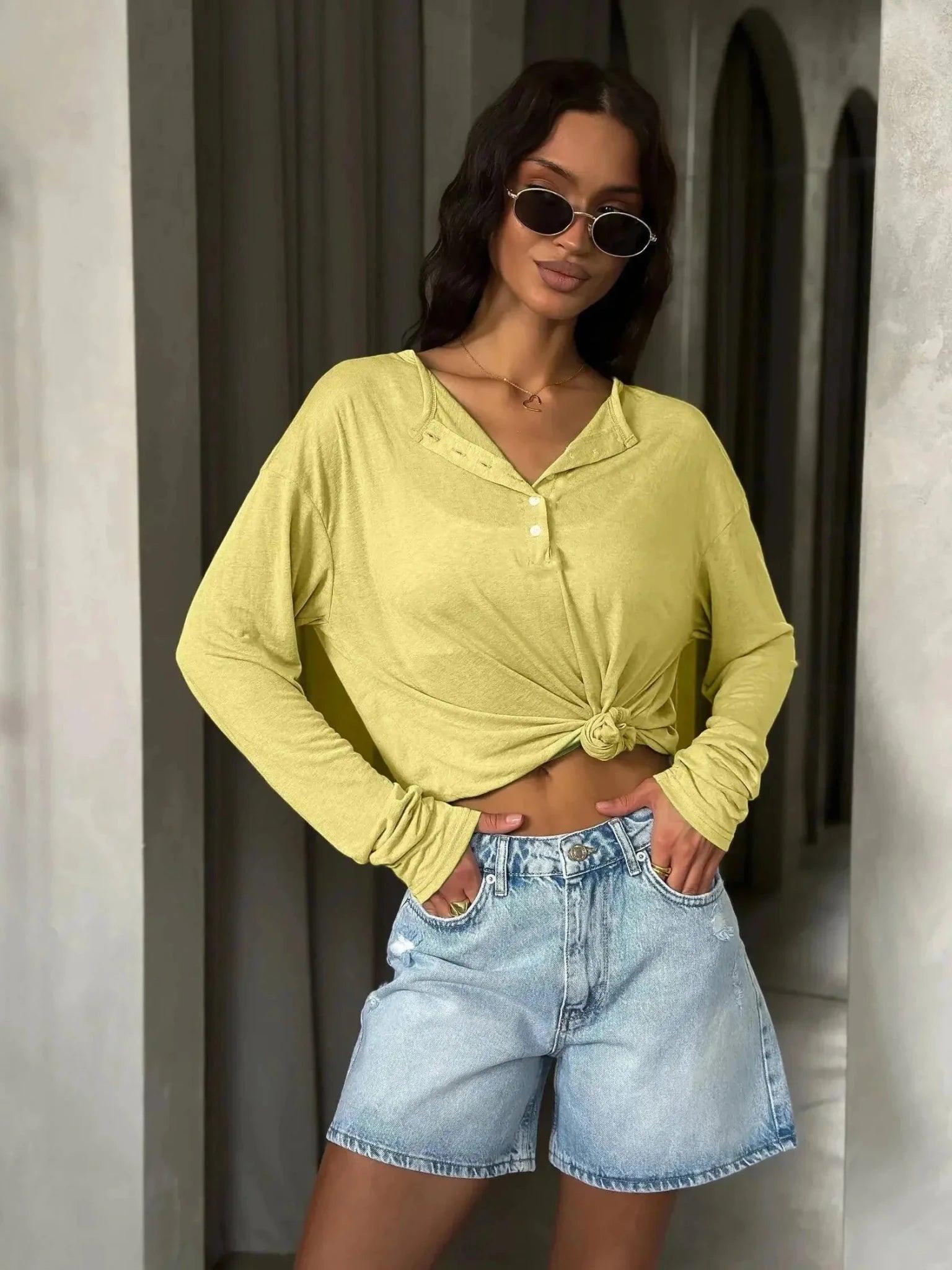 Woman in yellow knotted long sleeve top and denim shorts, stylish summer fashion outfit