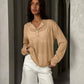 Woman in beige long sleeve button-up top and white denim shorts, stylish casual fashion outfit