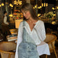Woman in stylish denim overalls and white blouse at chic restaurant, fashion outfit inspiration