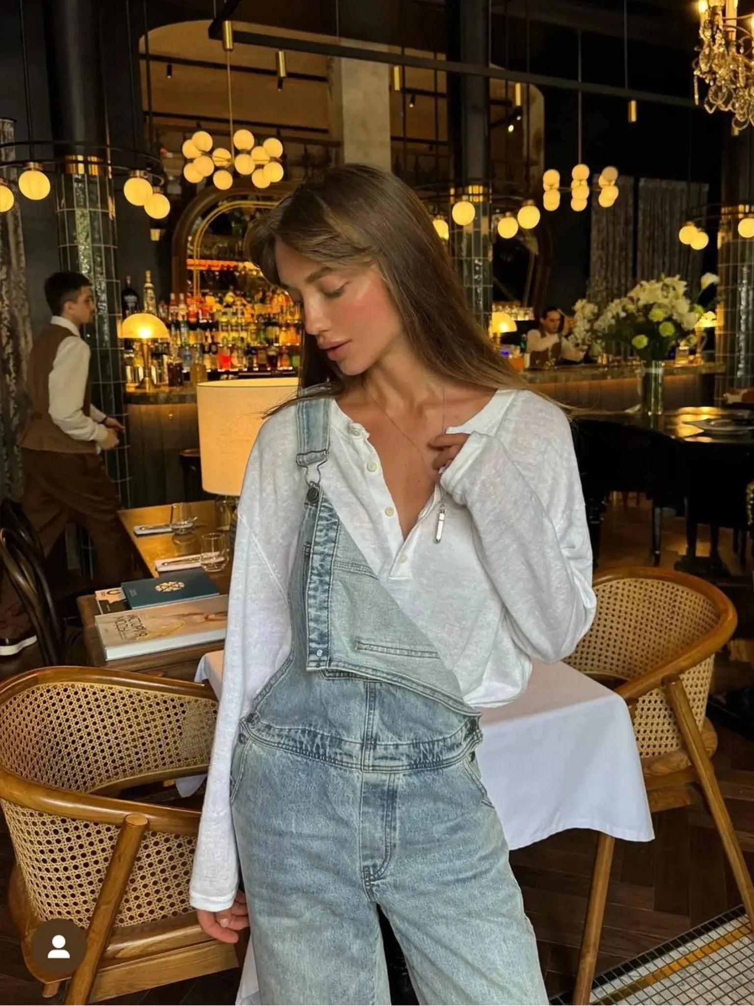 Woman in stylish denim overalls and white blouse at chic restaurant, fashion outfit inspiration