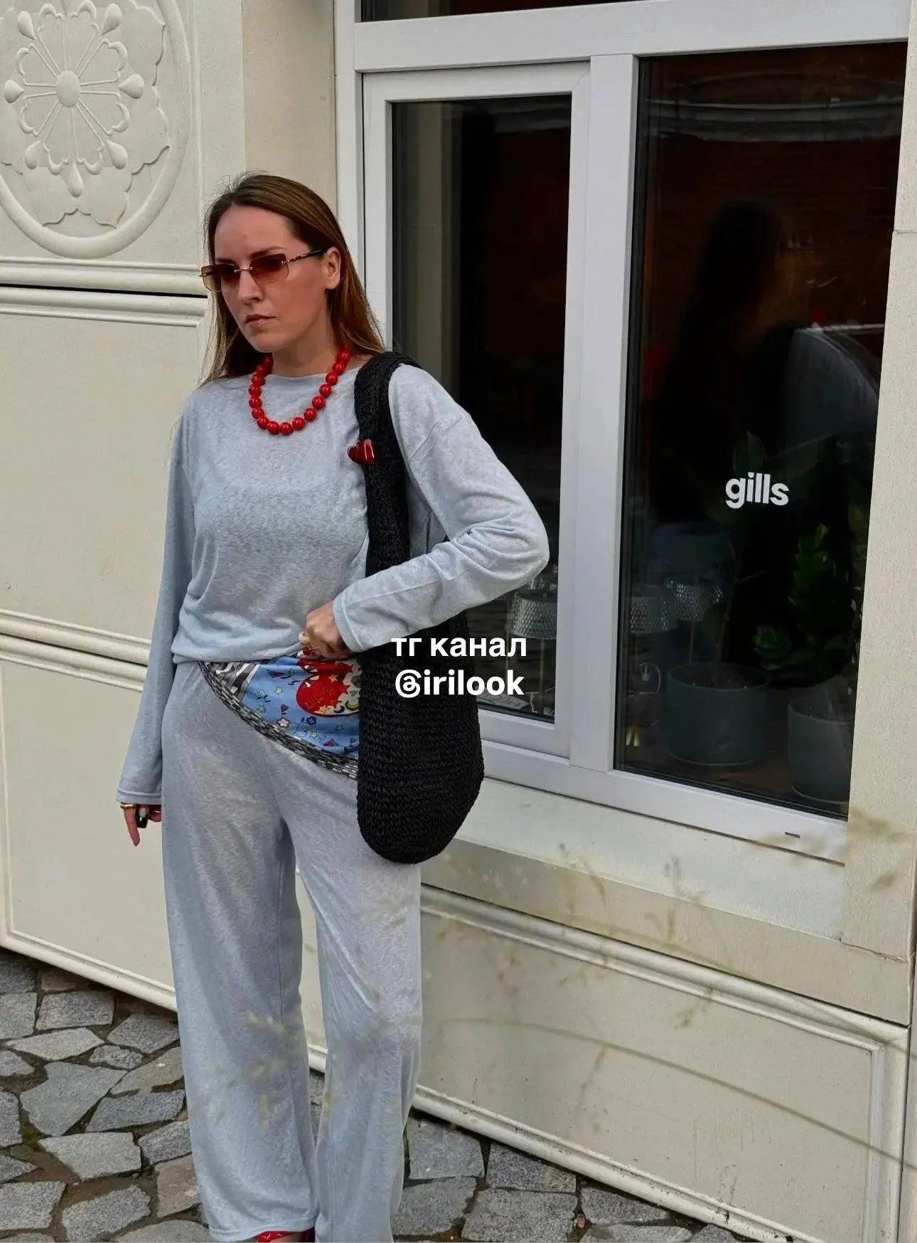 Woman in gray loungewear set with red beaded necklace and black woven bag, stylish street fashion