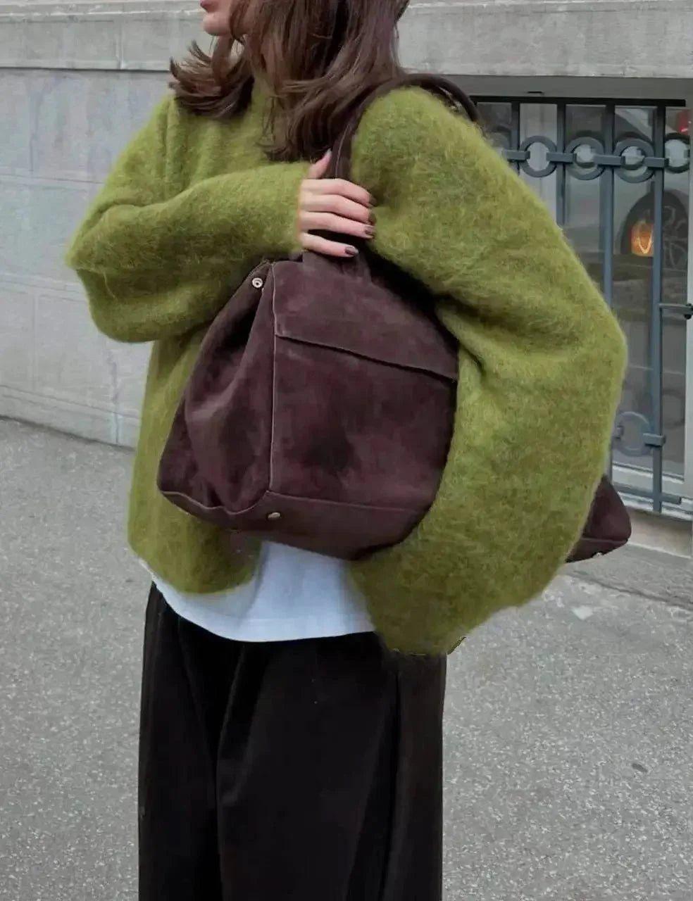 Woman in cozy green sweater carrying brown suede tote bag, street style fashion