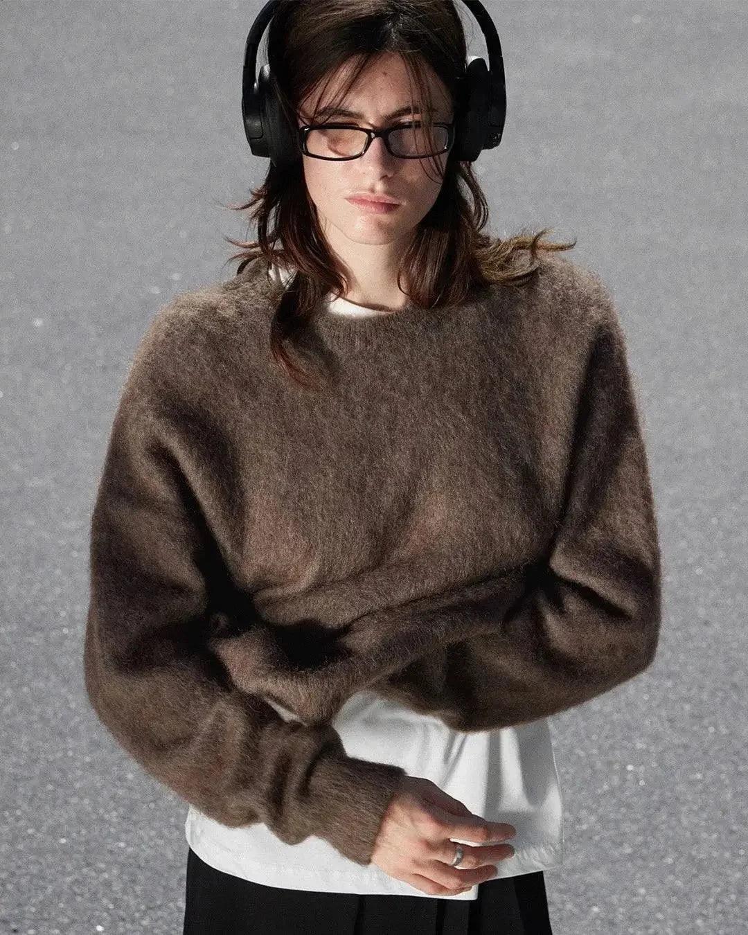 Woman wearing cozy brown sweater, glasses, and headphones for stylish everyday fashion