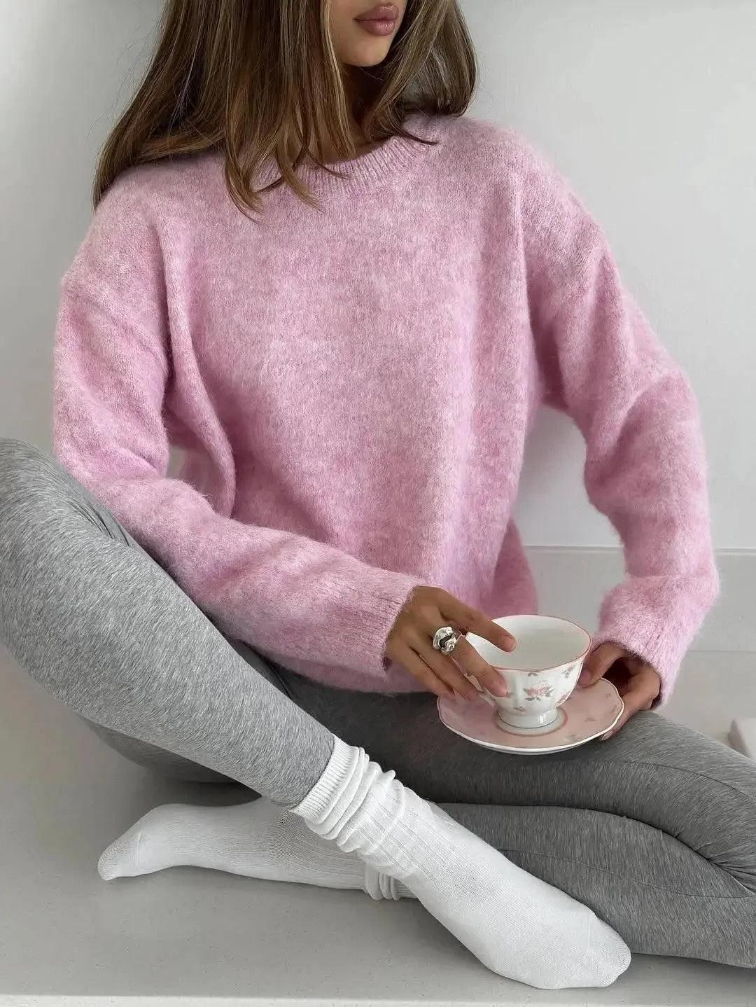 Woman in pink cozy sweater and gray leggings holding floral teacup, stylish casual fashion