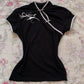 Black women's fashion top with white trim and floral design, laid on floral bedding