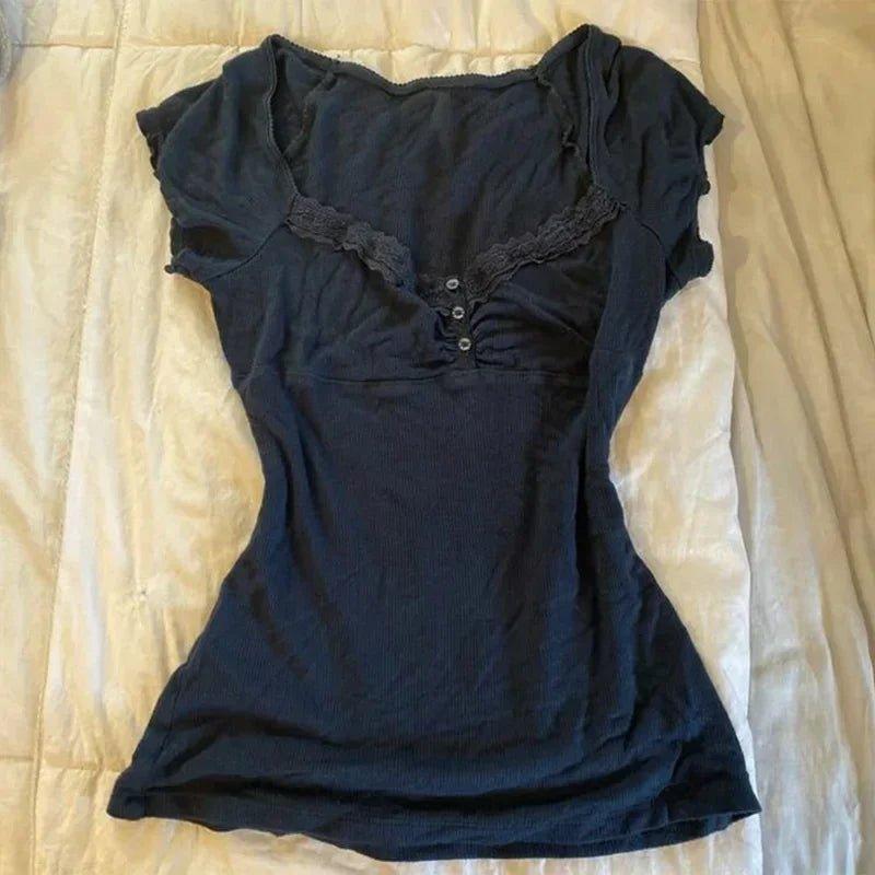 Black women's lace-trimmed button-front top with ruched detailing, laid flat on beige bedding