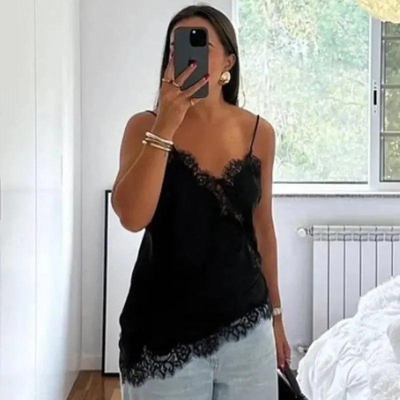 Woman wearing black lace camisole top with spaghetti straps, paired with light denim shorts, taking mirror selfie