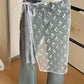Sheer floral lace wrap skirt with tie waist, worn over jeans for trendy women's fashion