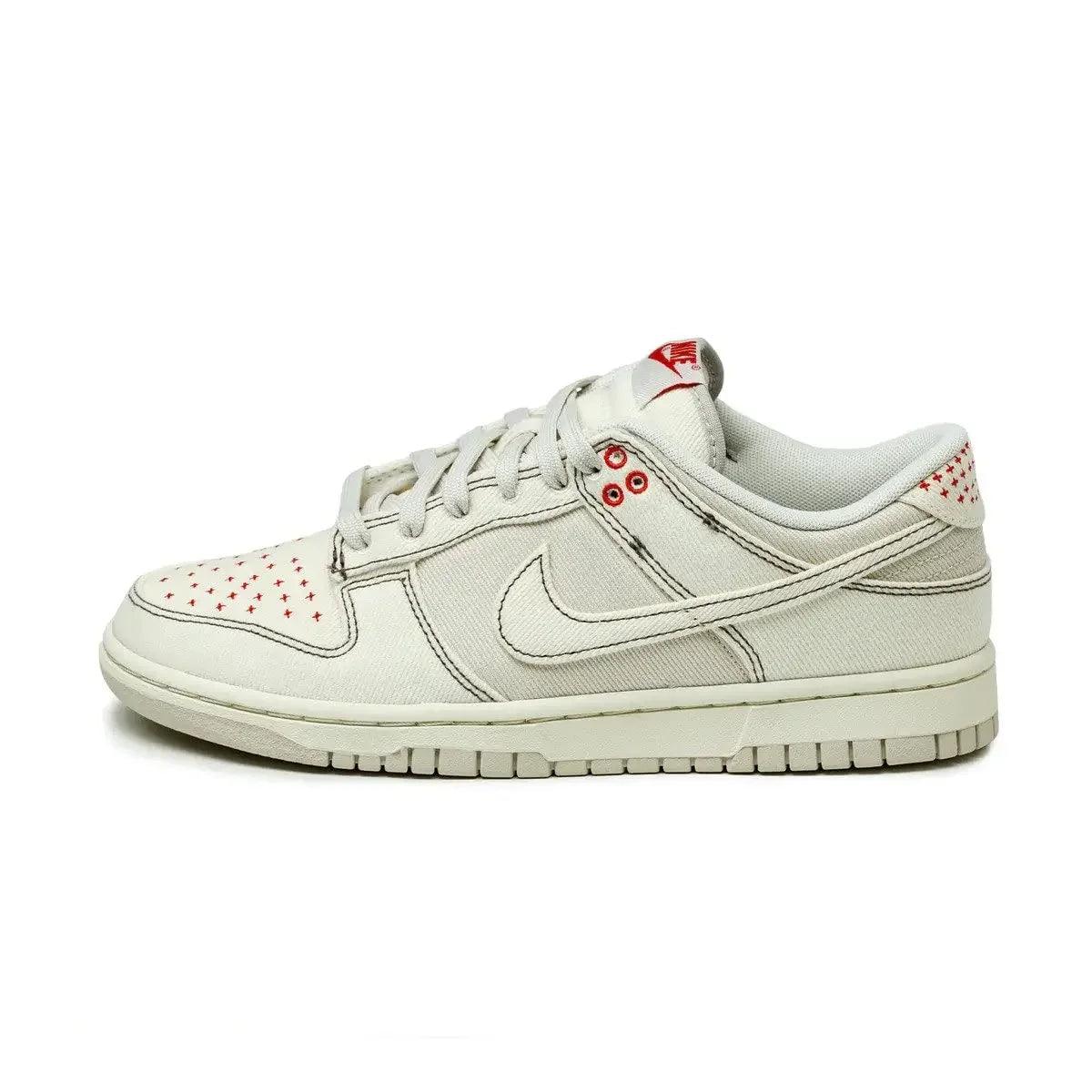 White Nike Dunk Low sneaker with red star accents, canvas texture, and classic design for women's fashion