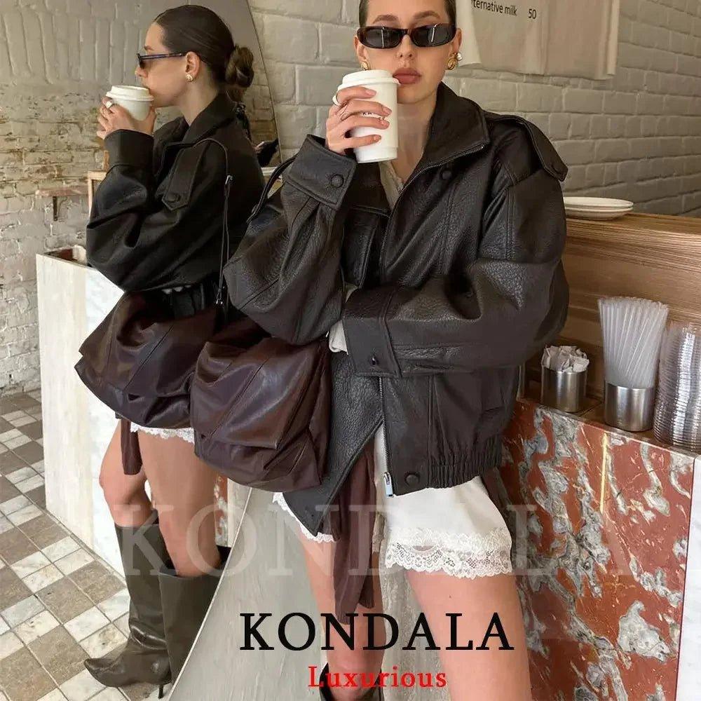 Woman in black leather jacket with lace shorts, holding coffee, stylish streetwear fashion