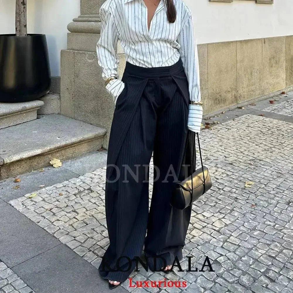 Woman in striped blouse and wide-leg black trousers, stylish street fashion outfit