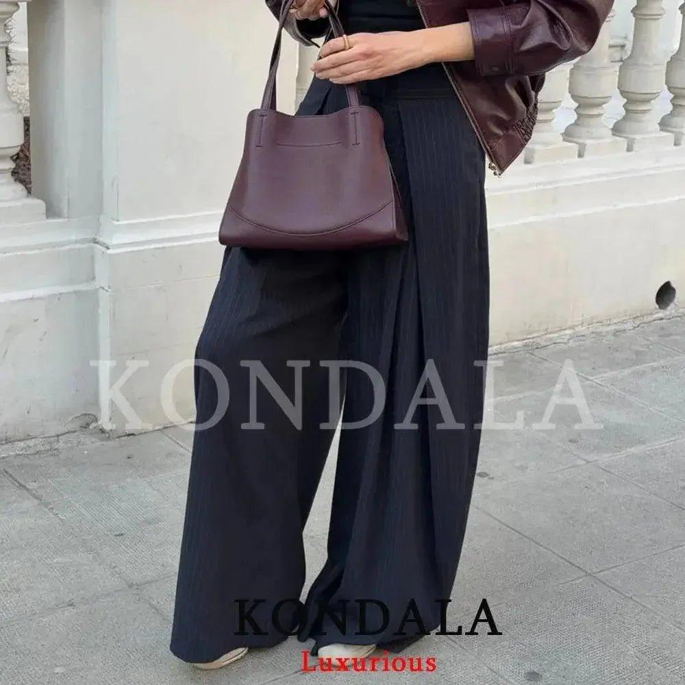 Woman in wide-leg pants and burgundy leather tote bag, stylish streetwear fashion
