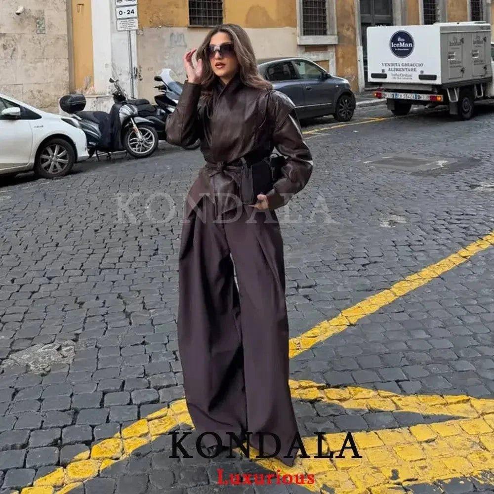 Woman in chic brown leather jumpsuit, stylish street fashion, wide-leg design, urban cobblestone backdrop