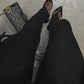 Black pointed-toe flats with ankle strap, paired with black pants and geometric print bag