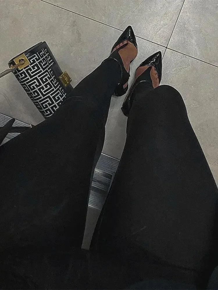 Black pointed-toe flats with ankle strap, paired with black pants and geometric print bag