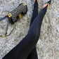 Black tights with pointed-toe flats and patterned handbag on fluffy rug, women's fashion