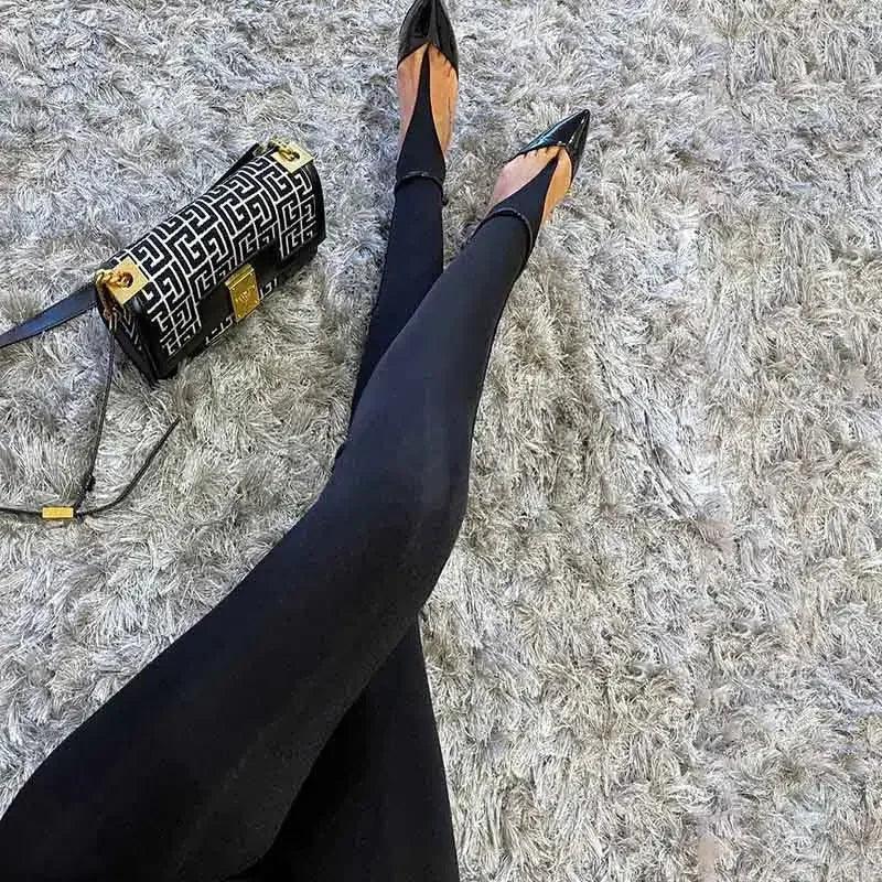 Black leggings with pointed-toe heels and patterned handbag on fluffy rug
