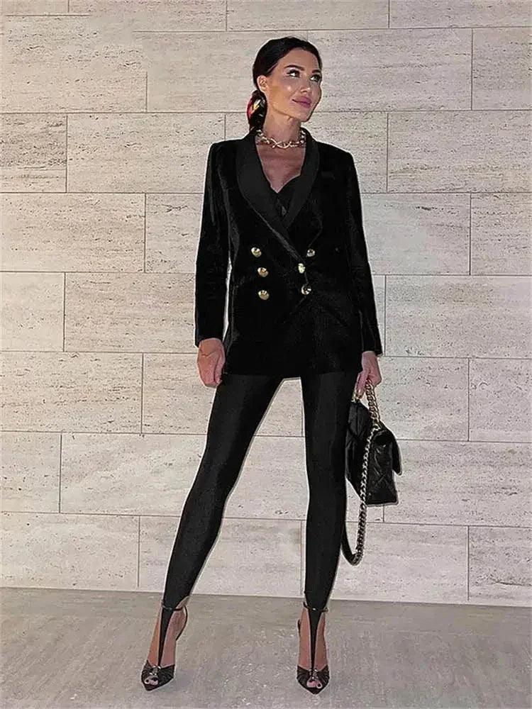 Woman in black velvet blazer with gold buttons, matching pants, heels, and chain bag — chic fashion outfit