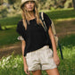 Woman in black tee, beige shorts, and corduroy bucket hat outdoors
