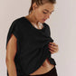 Woman in black workout top and shorts, wearing white sunglasses, post-exercise look
