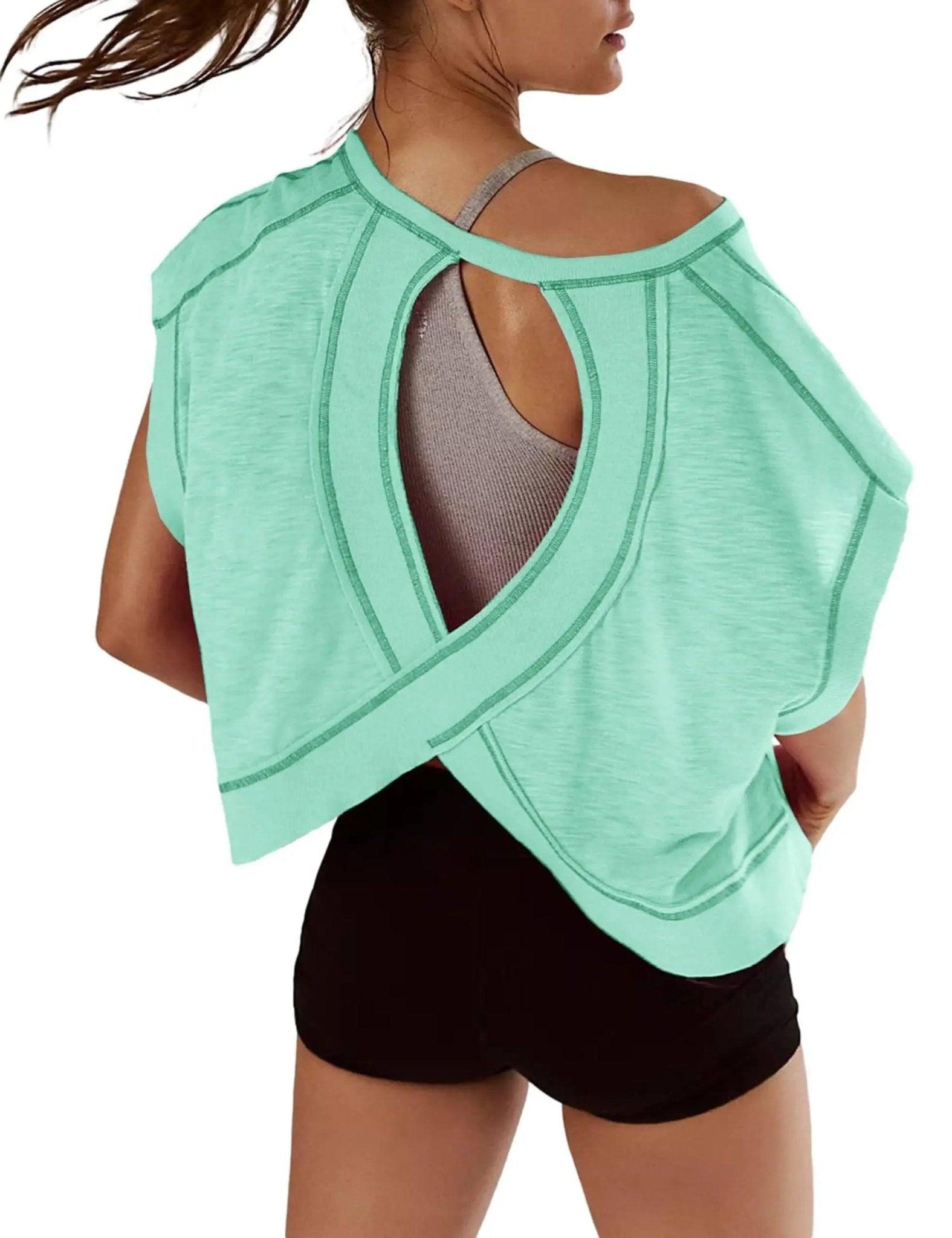Mint green open-back workout top with crisscross design, paired with black shorts for women's active fashion