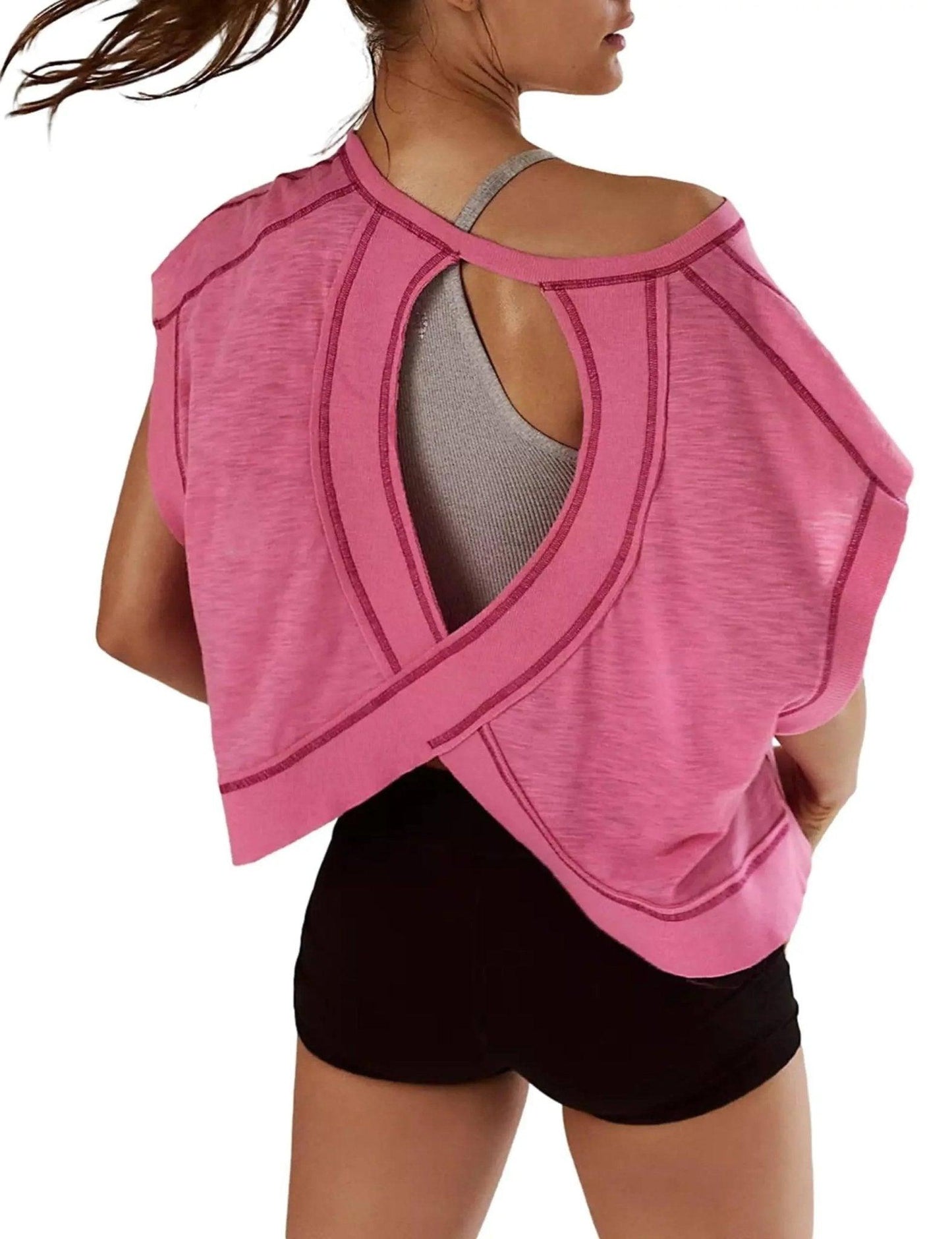 Pink women's workout top with open back design, paired with black shorts for gym or yoga