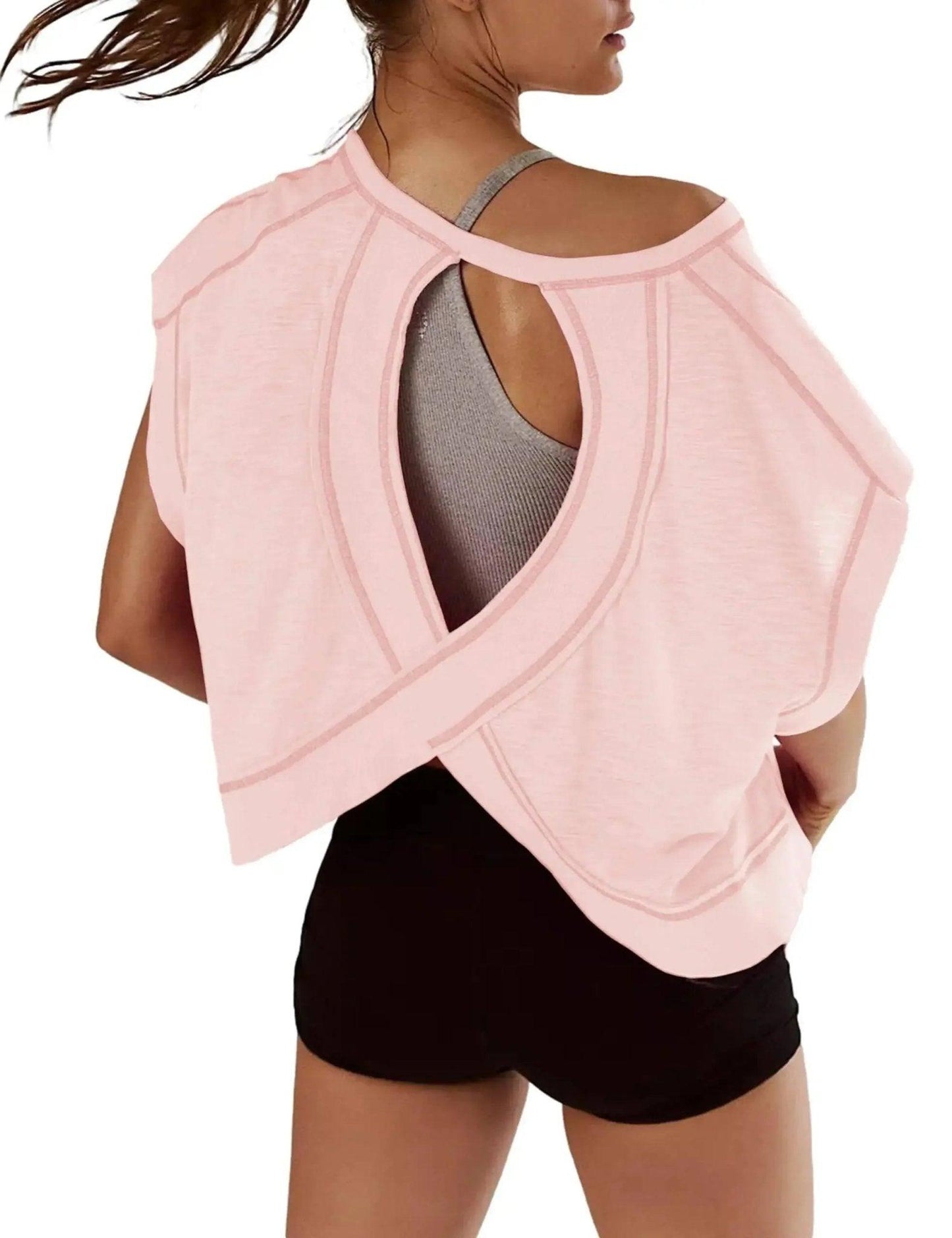 Pink open-back workout top with crisscross design, paired with black shorts for women's fashion fitness wear
