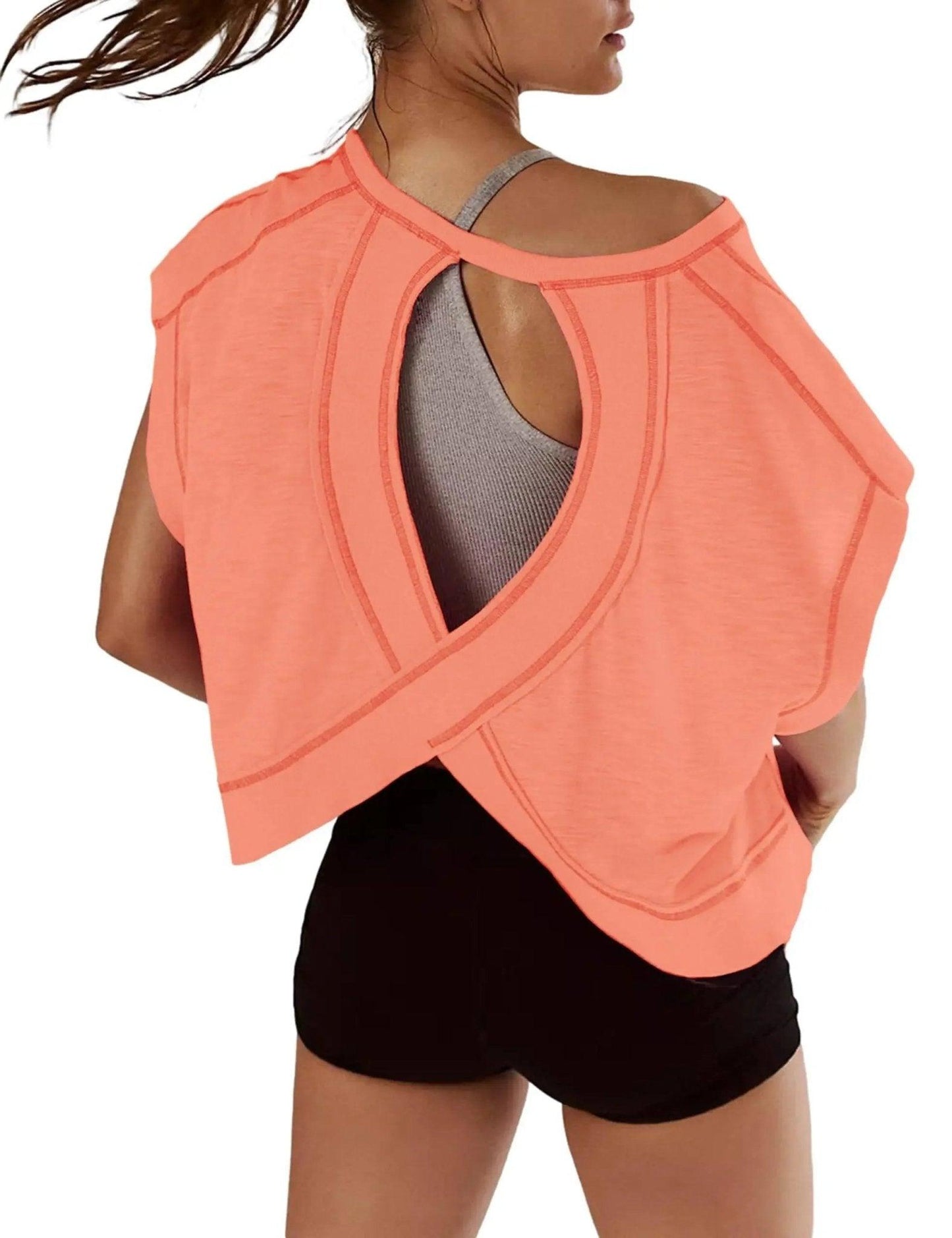 Coral open-back workout top with crisscross design, paired with black shorts for women's active fashion