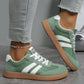 Green and white women's fashion sneakers with striped design, paired with ripped jeans