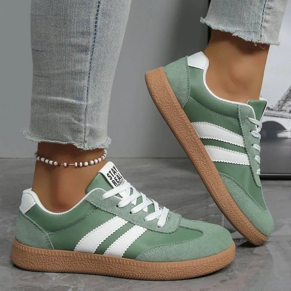 Green and white women's fashion sneakers with striped design, paired with ripped jeans