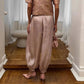 Woman in rose gold textured top, satin balloon pants, and pink heels — elegant fashion outfit