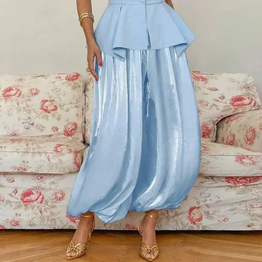 Light blue peplum top with shiny wide-leg pants, gold heels, floral sofa background
