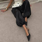Woman in black satin balloon pants, polka dot top, and pointed heels, stylish fashion outfit