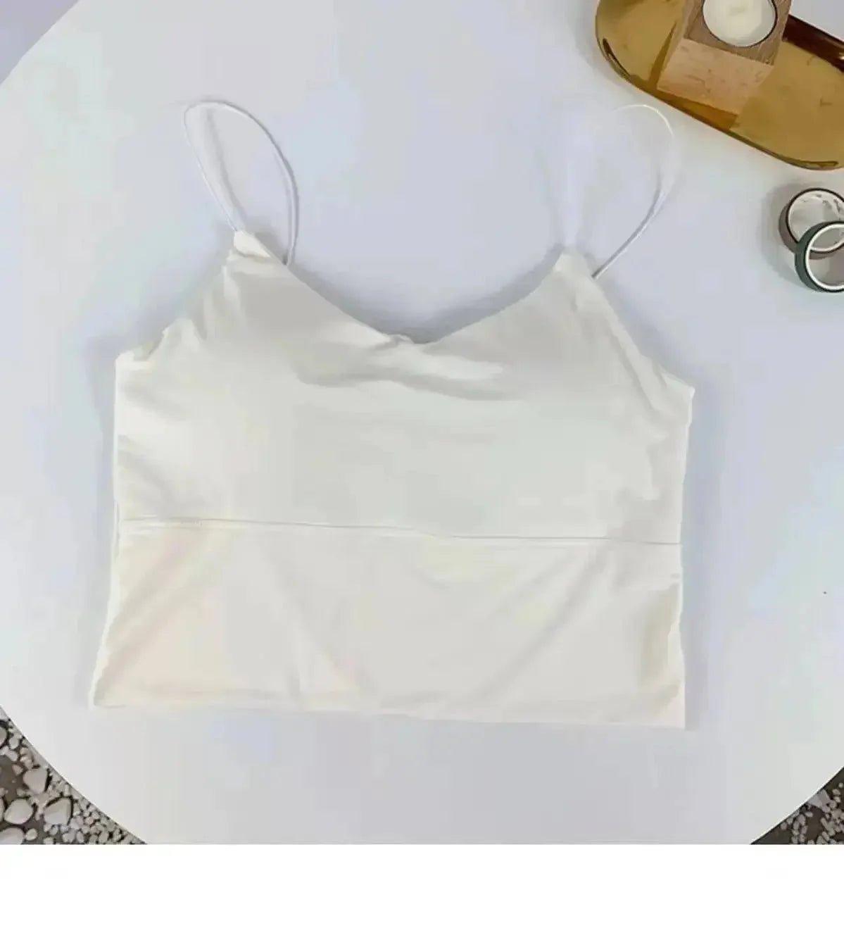 White satin camisole top with thin straps, laid flat on white surface for women's fashion