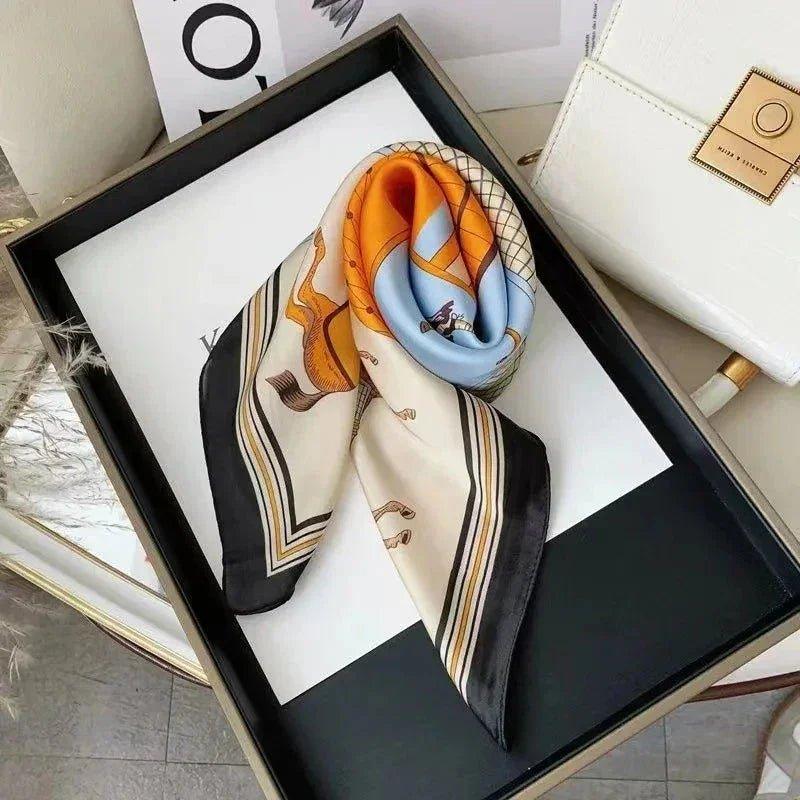 Elegant women's silk scarf with horse print, orange and blue accents, styled in luxury gift box for fashion accessories.