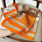 Orange horse print silk scarf for women, stylish fashion accessory on chair with magazine