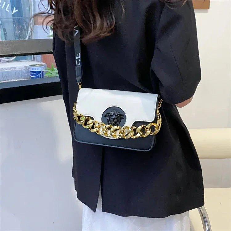 White and black women's crossbody bag with gold chain and Medusa emblem, fashion accessory