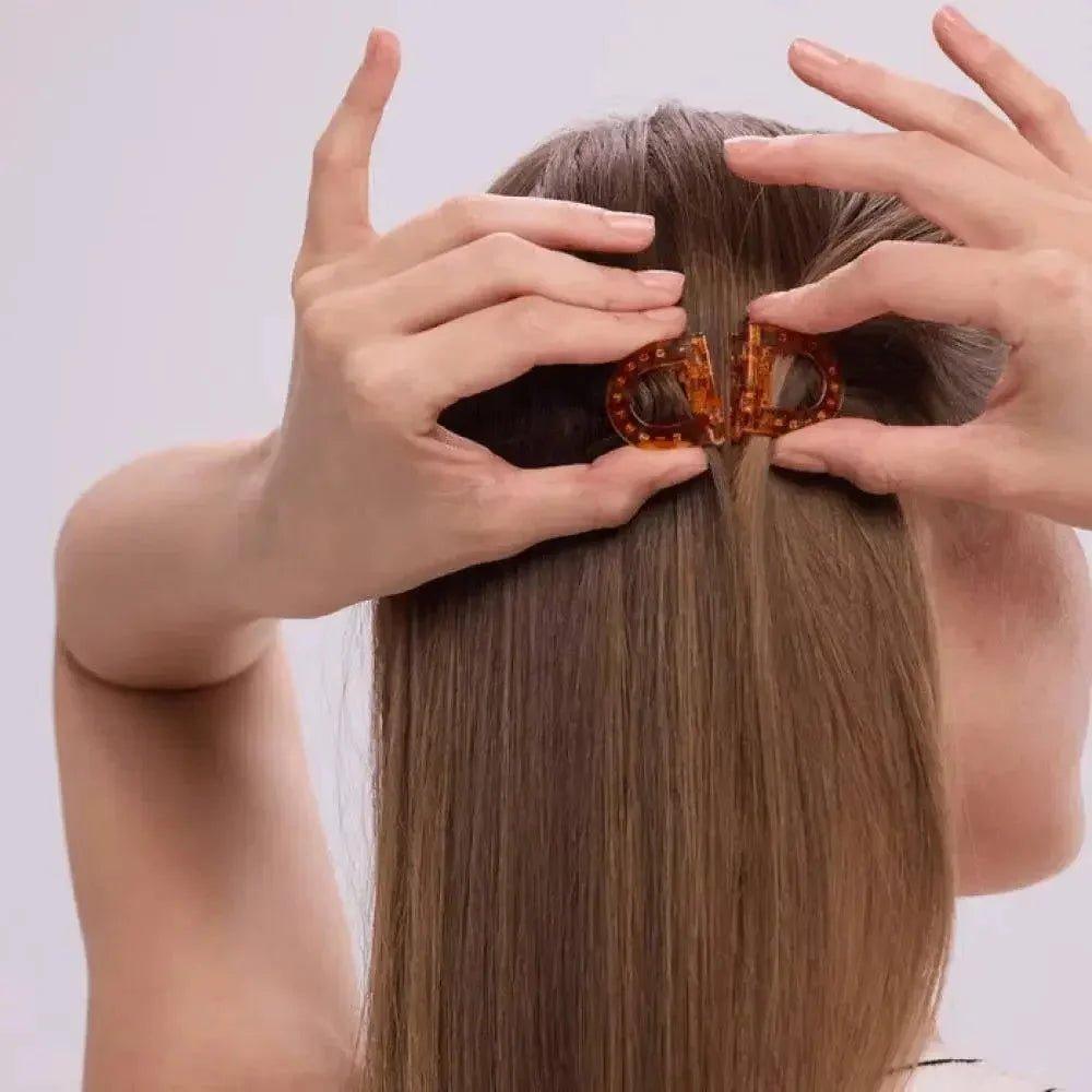 Woman styling hair with tortoiseshell hair clip, fashion accessory for sleek updo