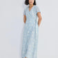 Woman in light blue floral wrap dress with short sleeves and tie waist, paired with strappy sandals