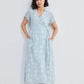 Woman in light blue floral wrap dress with short sleeves and tie waist, paired with strappy sandals