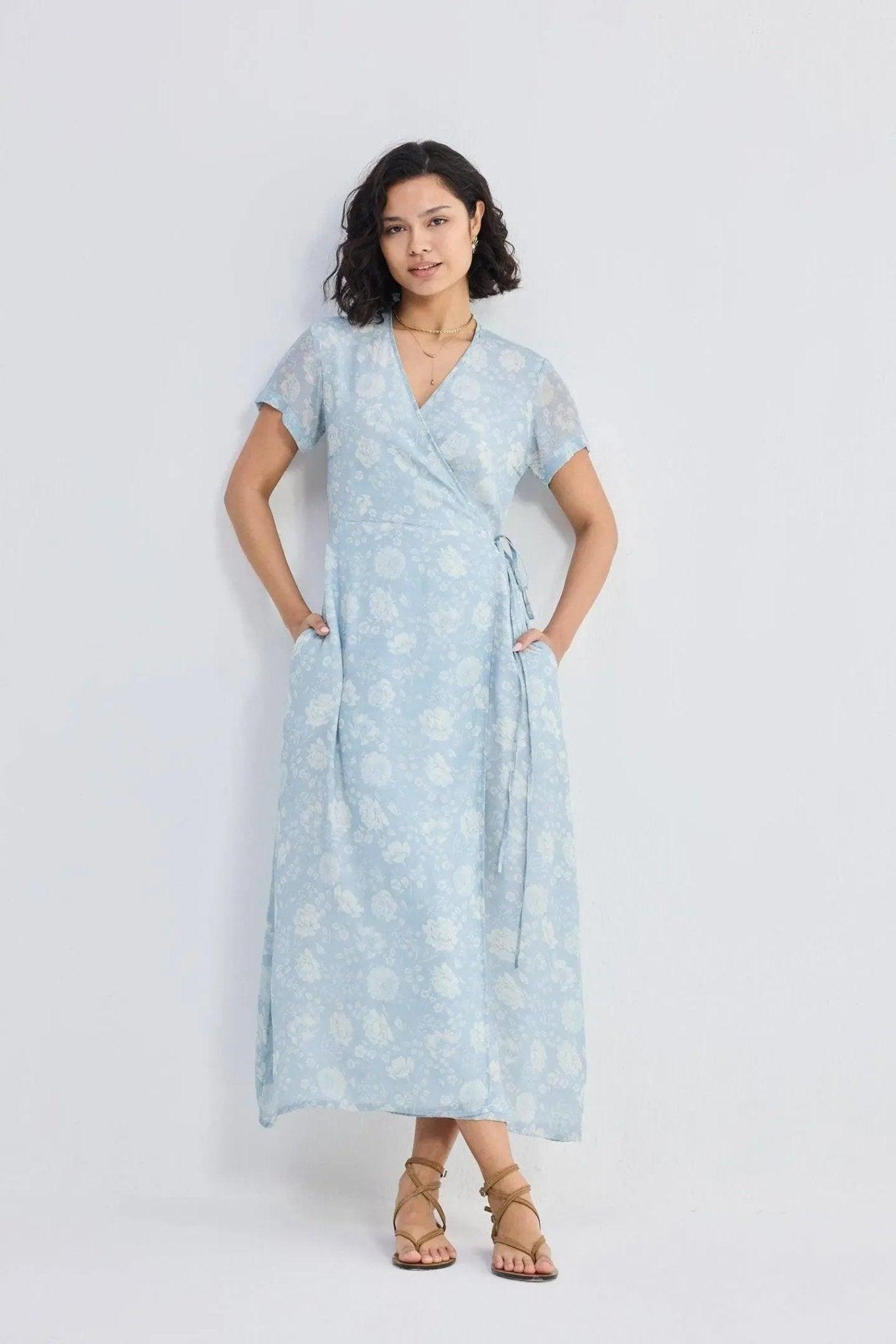 Woman in light blue floral wrap dress with short sleeves and tie waist, paired with strappy sandals