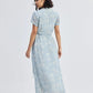 Woman in light blue floral midi dress with short sleeves and tie waist, back view