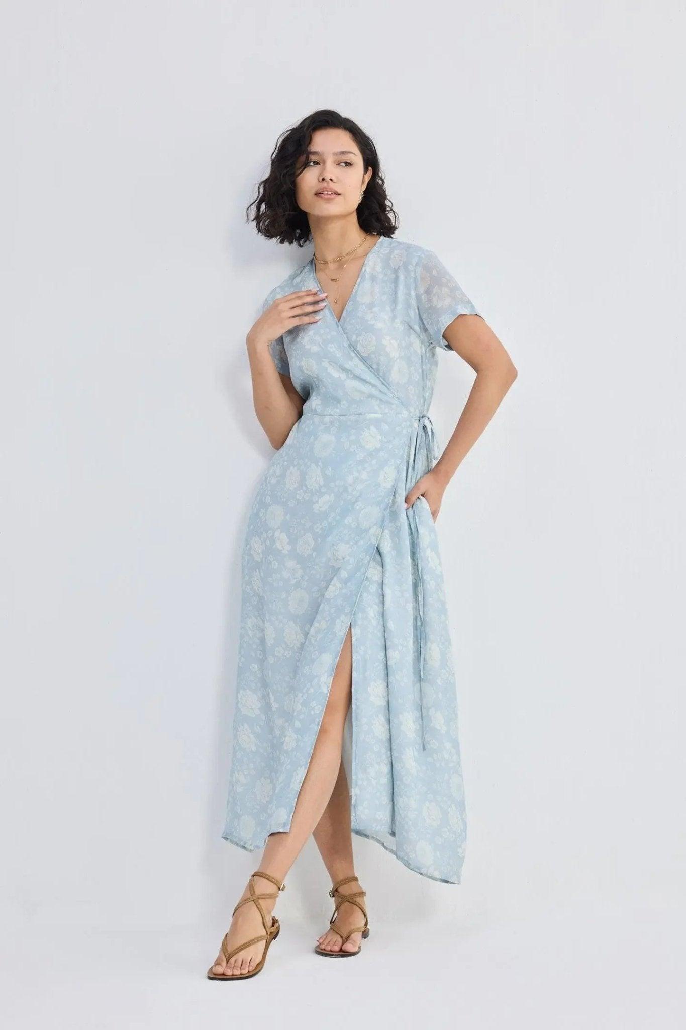 Woman in light blue floral wrap dress with slit, paired with strappy sandals, for summer fashion