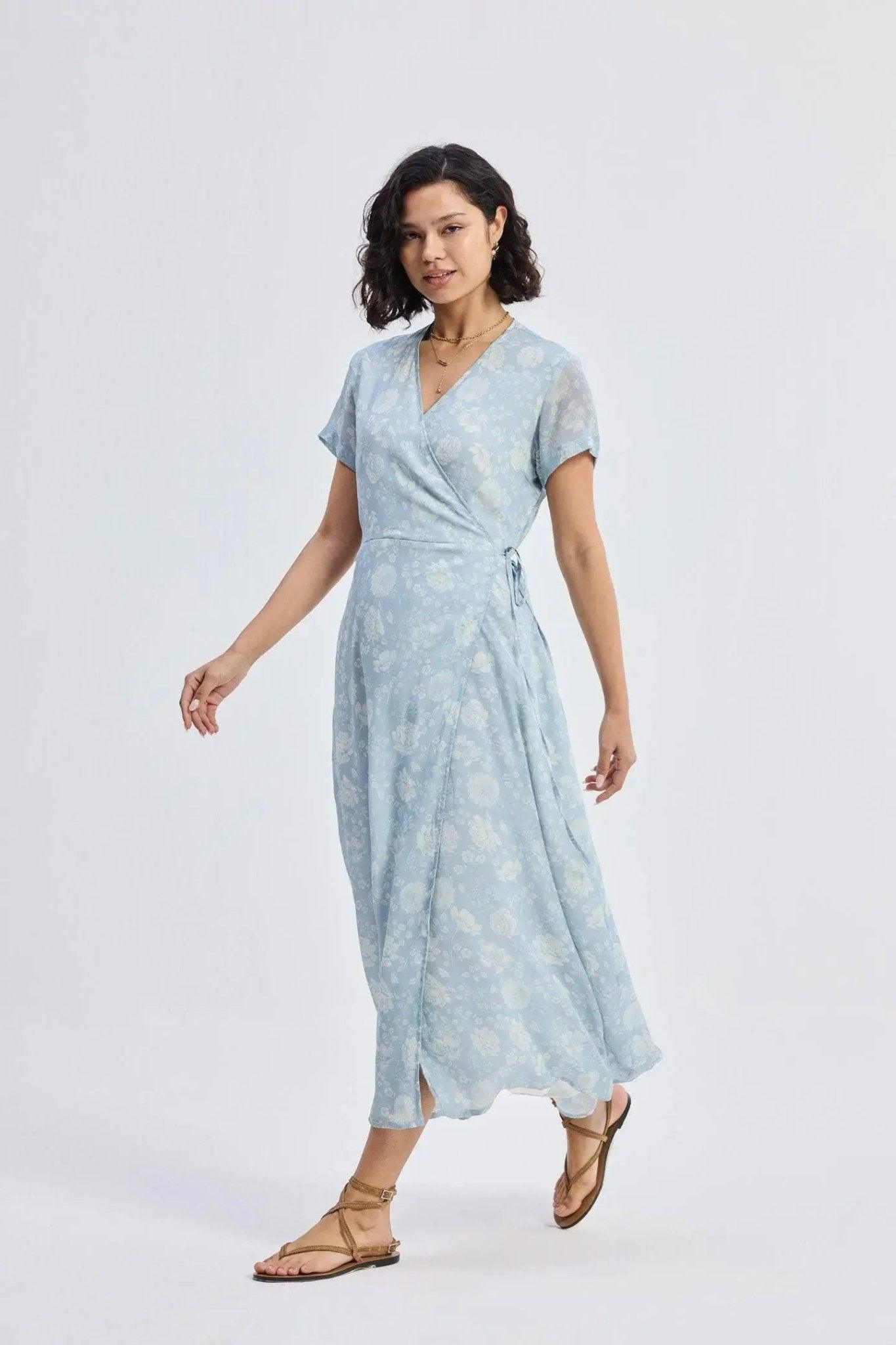 Woman in light blue floral wrap dress with short sleeves and sandals, stylish summer fashion