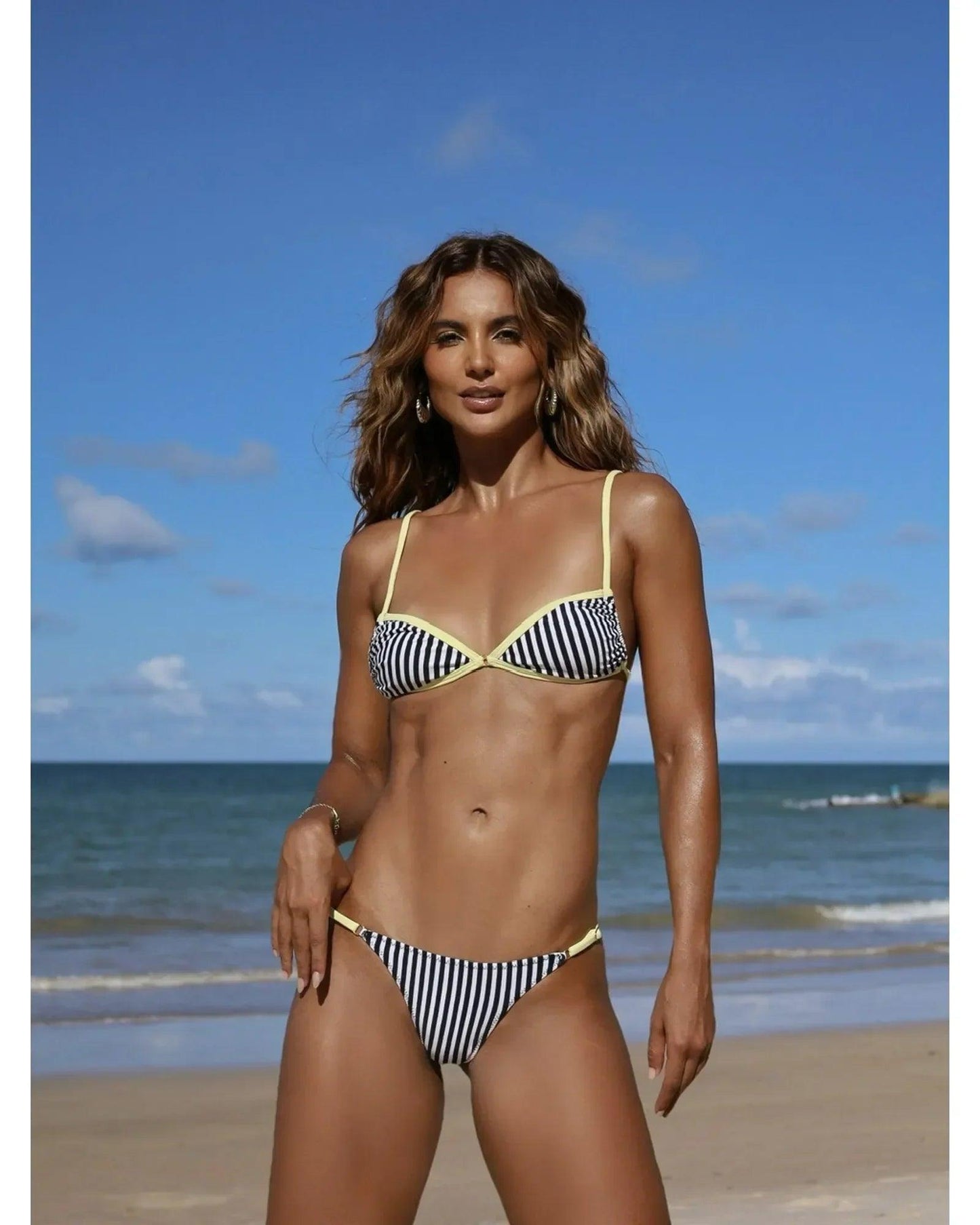 Woman in striped bikini on beach, summer fashion swimwear