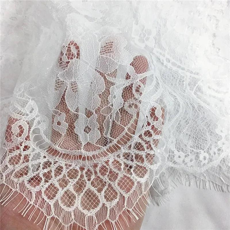 Delicate white floral lace fabric with scalloped edge, perfect for women's fashion dresses and bridal wear