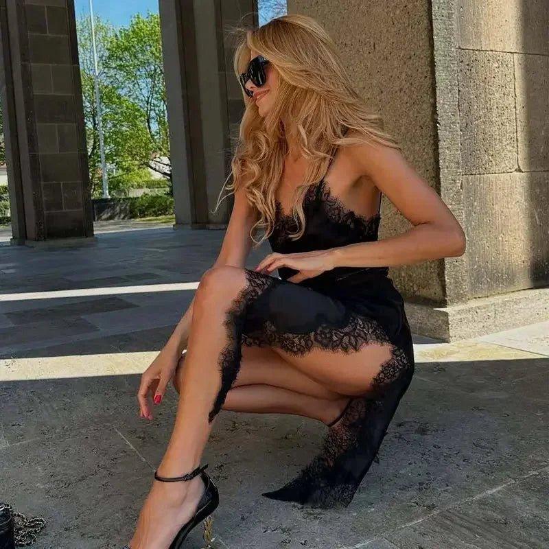 Woman in black lace dress and heels, posing outdoors