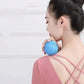 Woman using blue spiky massage ball on shoulder for muscle relief