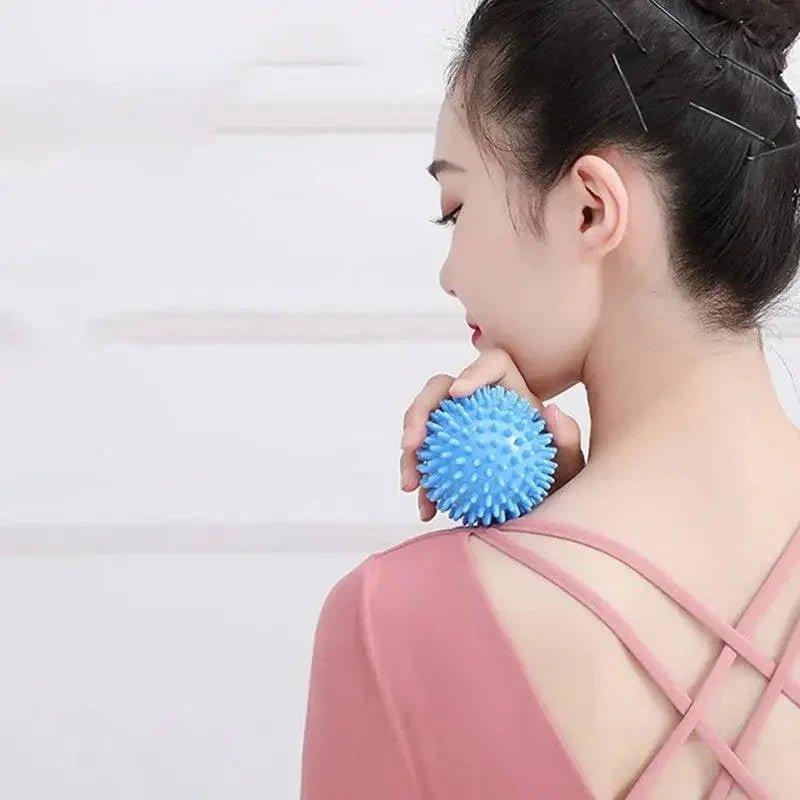 Woman using blue spiky massage ball on shoulder for muscle relief
